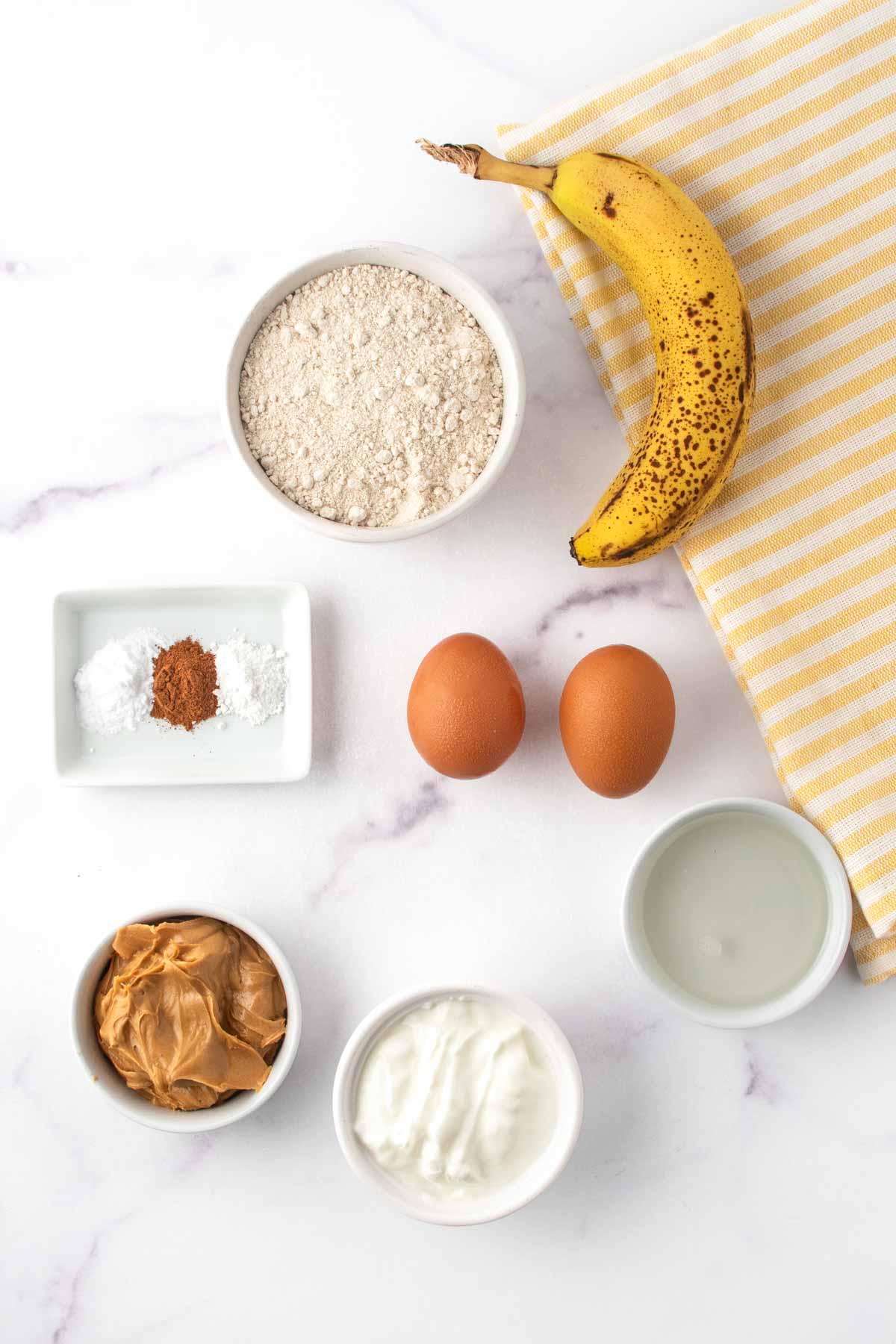 Homemade banana muffins for dogs ingredients on a marble surface.