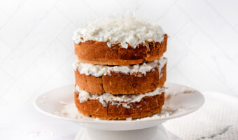 Homemade coconut cake for dogs on a cake stand and a kitchen towel next to it.