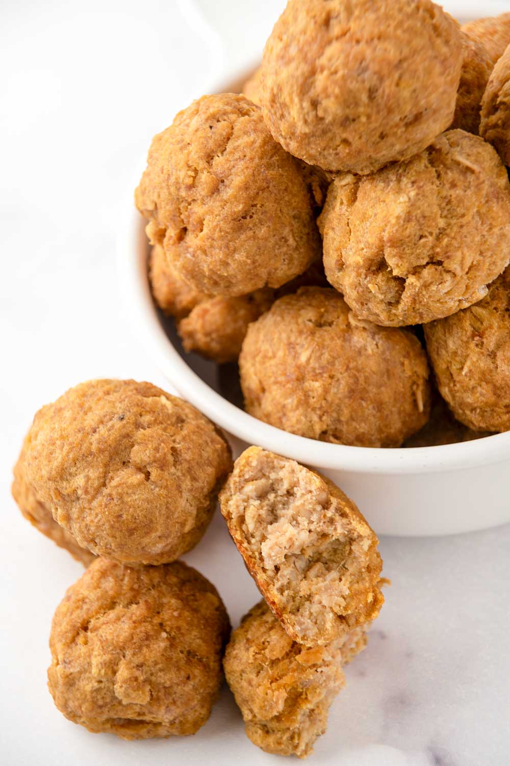 Homemade turkey pumpkin meatballs for dogs beside and in a small bowl.