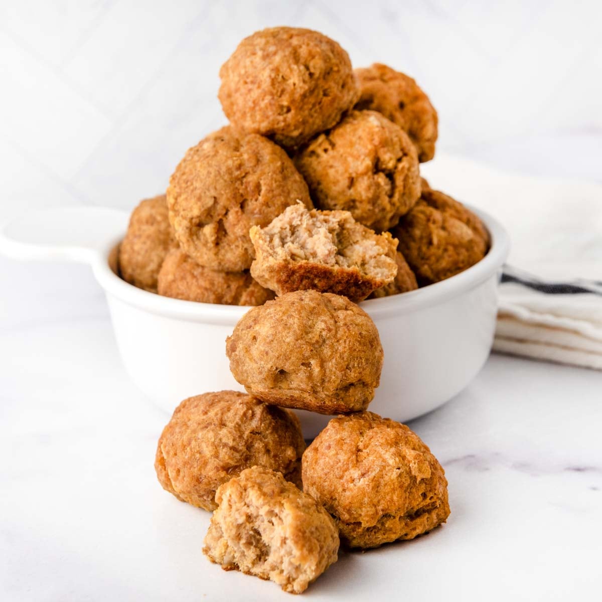 Homemade turkey pumpkin meatballs for dogs in front of and in a bowl.