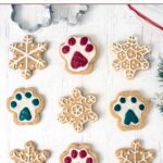 Homemade Christmas dog treats with icing in snowflake and paw print shapes.