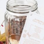 Homemade dog treat mix in a jar with a recipe card attached to it.