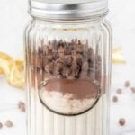 Homemade dog treat mix in a jar on a marble surface.