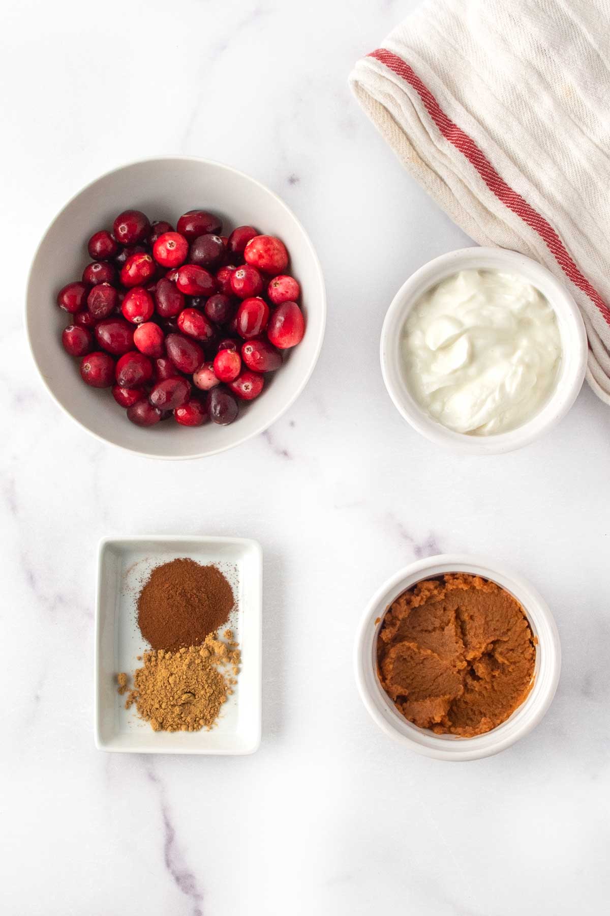 Homemade frozen cranberry dog treats ingredients on a marble surface.