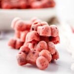 Homemade frozen cranberry dog treats on a marble surface.