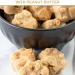 Homemade paw-shaped goat milk dog treats with peanut butter in front of and in a bowl.