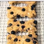 Homemade bone-shaped blueberry dog treats on a wire rack.