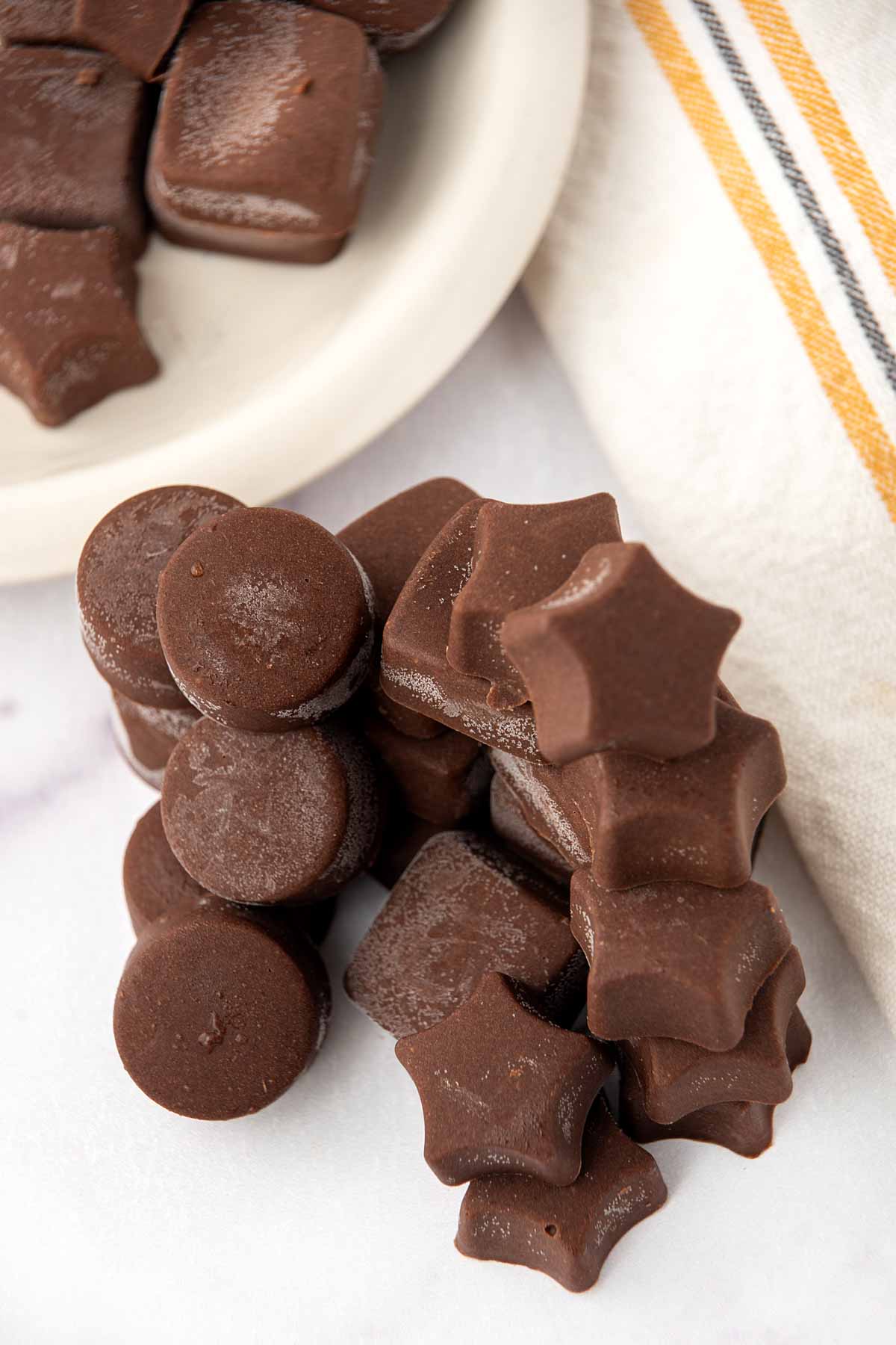 Homemade carob peanut butter candy for dogs in a bowl and stacked beside it.