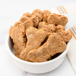 Homemade carrot cake dog treats in a small bowl.