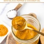 Homemade turmeric golden paste for dogs on a spoon on top of a jar of it.