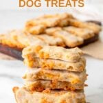 Homemade bone-shaped cheese dog treats in a stack and on a small wood cutting board.