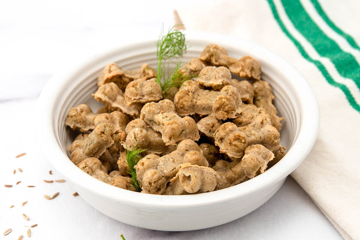 Homemade fennel dog treats and fennel fronds in a bowl and fennel seeds by it.