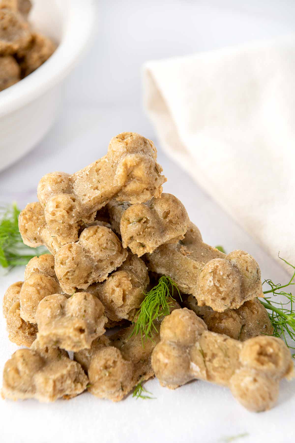 Homemade fennel dog treats and fennel fronds in a pile on a marble surface.