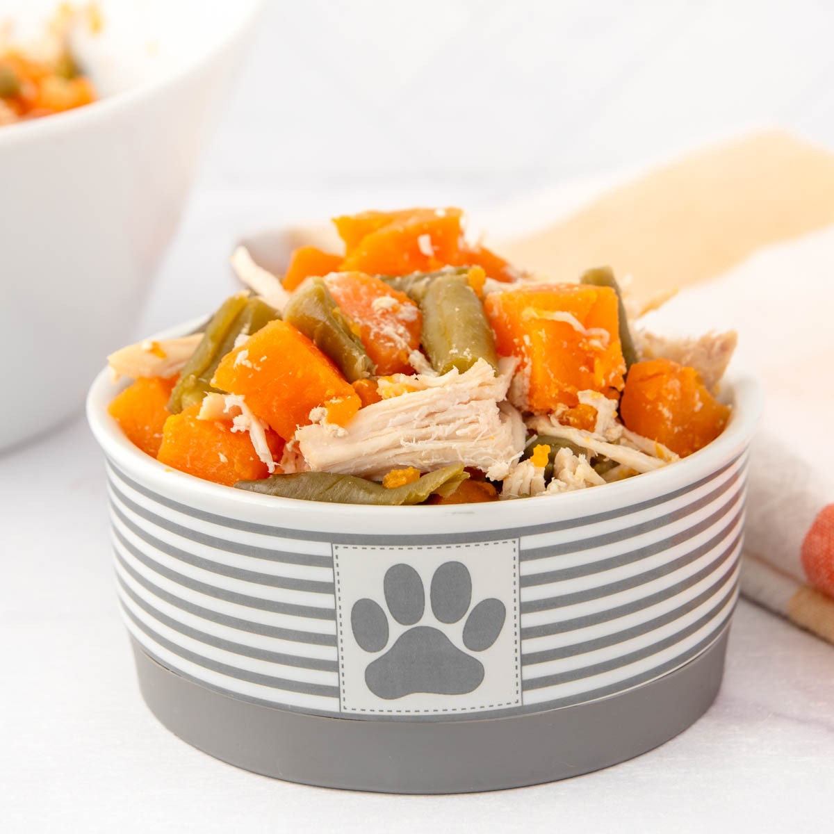 Slow cooker chicken and sweet potato dog food with green beans in a small dog food bowl.