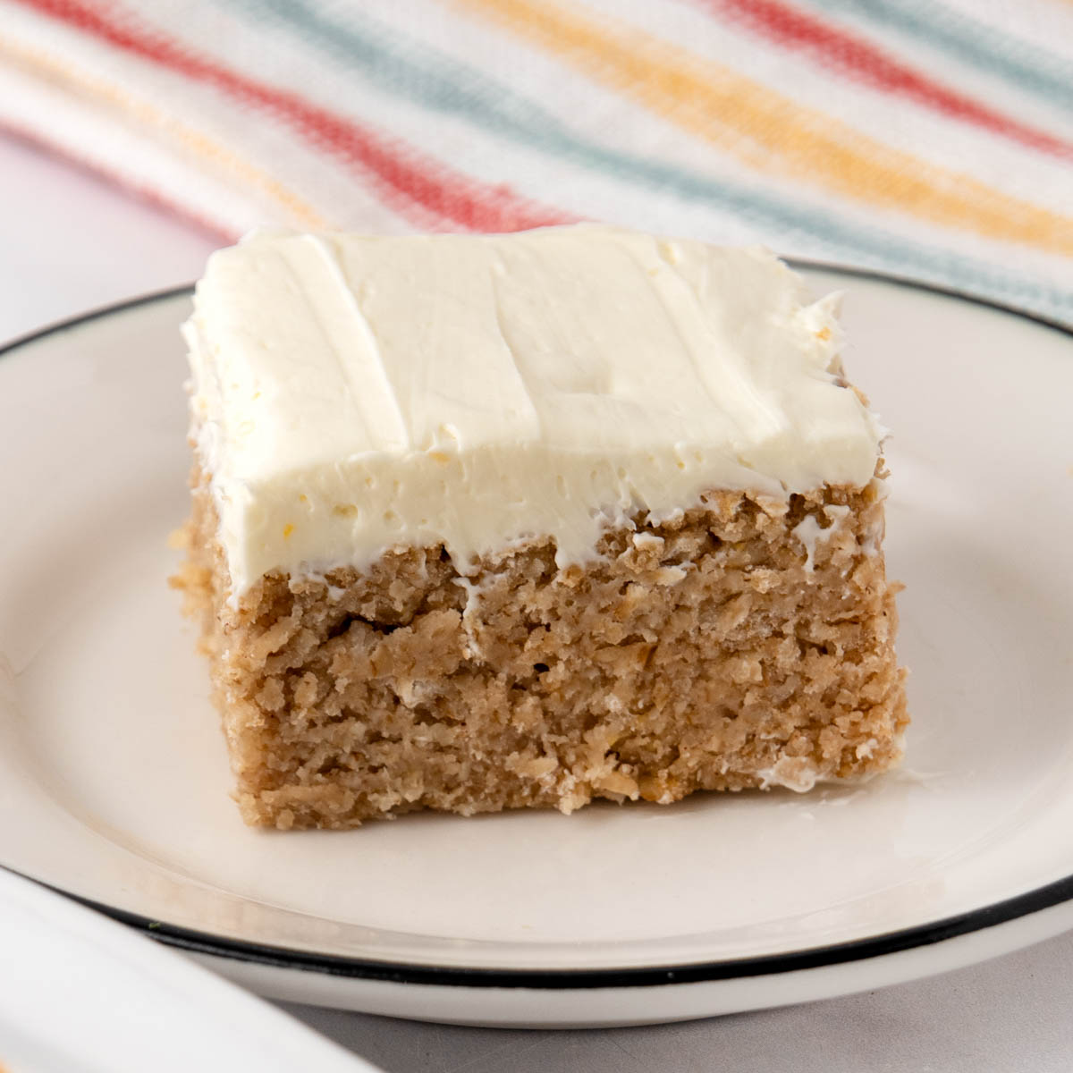 Homemade applesauce cake with cream cheese frosting on a plate.