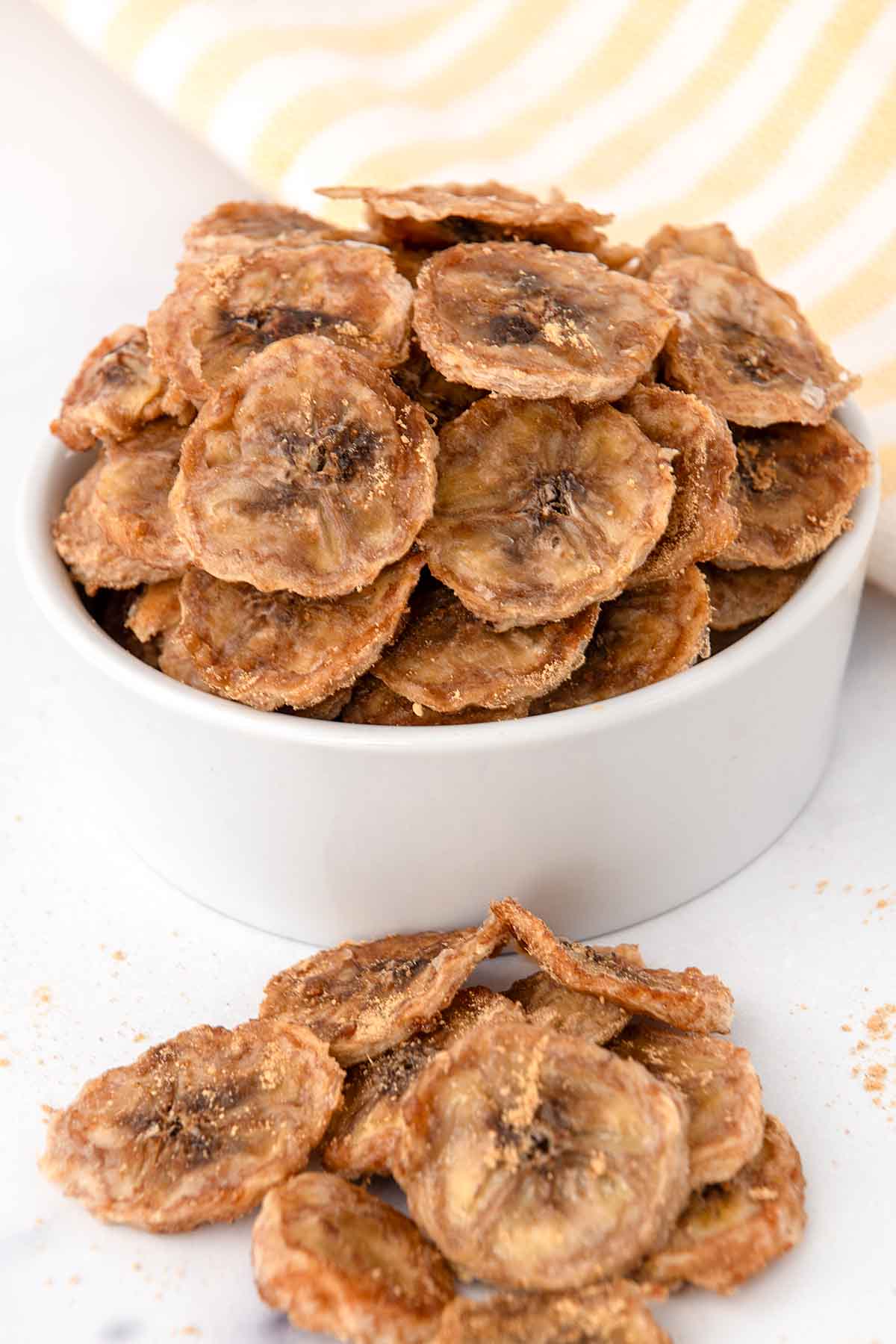 Homemade banana chips flavored with ginger in a bowl and next to it.