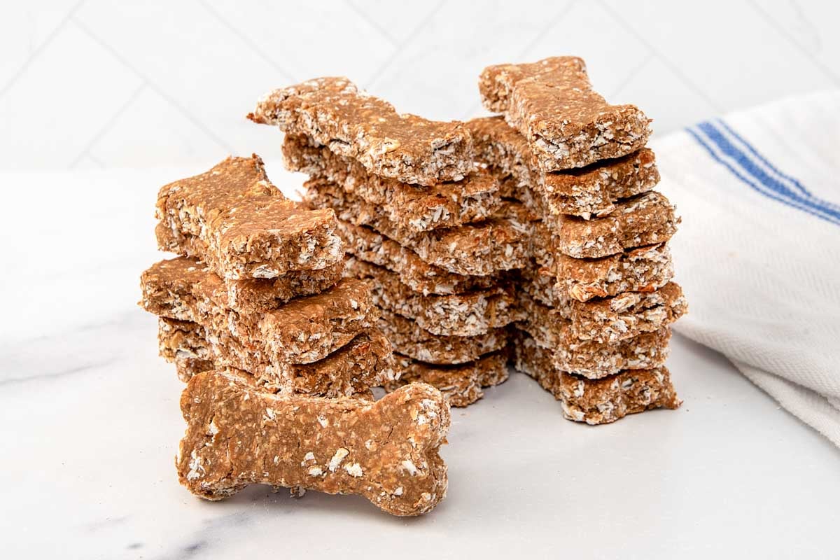 Bone-shaped homemade dog treats made with brewer's yeast, oats, and applesauce in stacks.