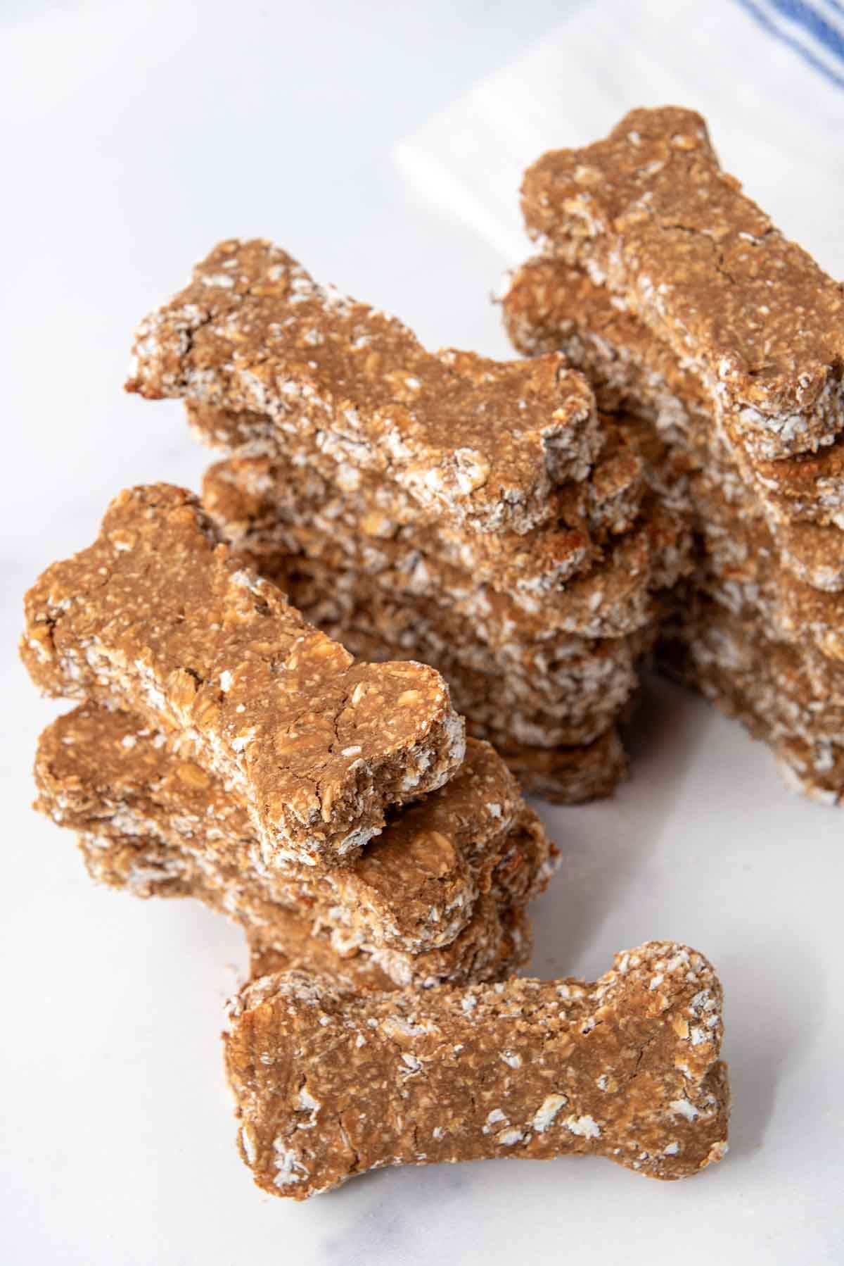 Stacks of homemade dog treats with brewer's yeast and oats on a marble surface.