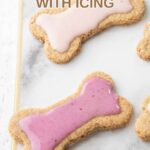 Two homemade dog cookies with icing on a marble platter.
