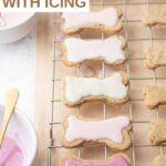 Homemade iced dog cookies on a rack and bowls of colored icing.