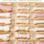 Homemade dog cookies with icing on a wire rack over parchment paper.