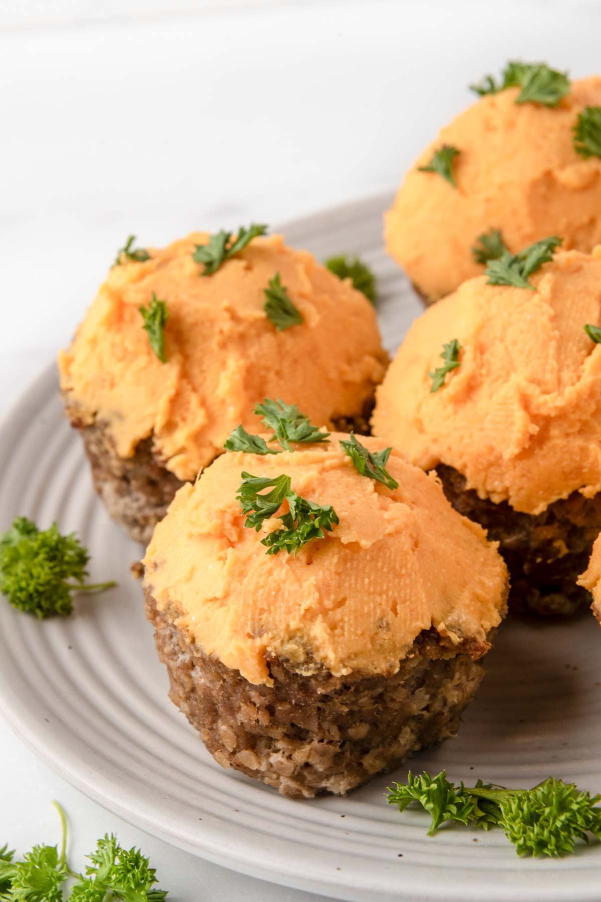 Homemade meatloaf pupcakes with sweet potato frosting garnished with curly parsley.