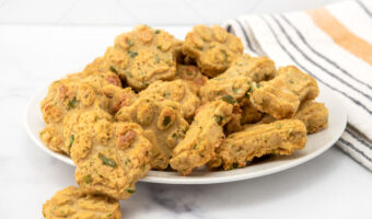 Homemade turkey and sweet potato dog treats in paw and bone shapes piled on a plate.