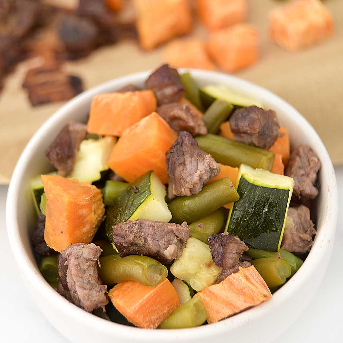 Sheet pan beef and veggie dog food served in a small bowl.