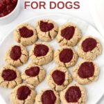 Homemade thumbprint cookies for dogs with strawberry jam filling on a plate.