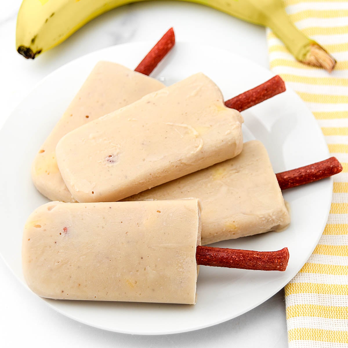Homemade banana popsicles for dogs on a plate.