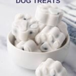 A bowl of paw-shaped frozen yogurt dog treats with fruit.