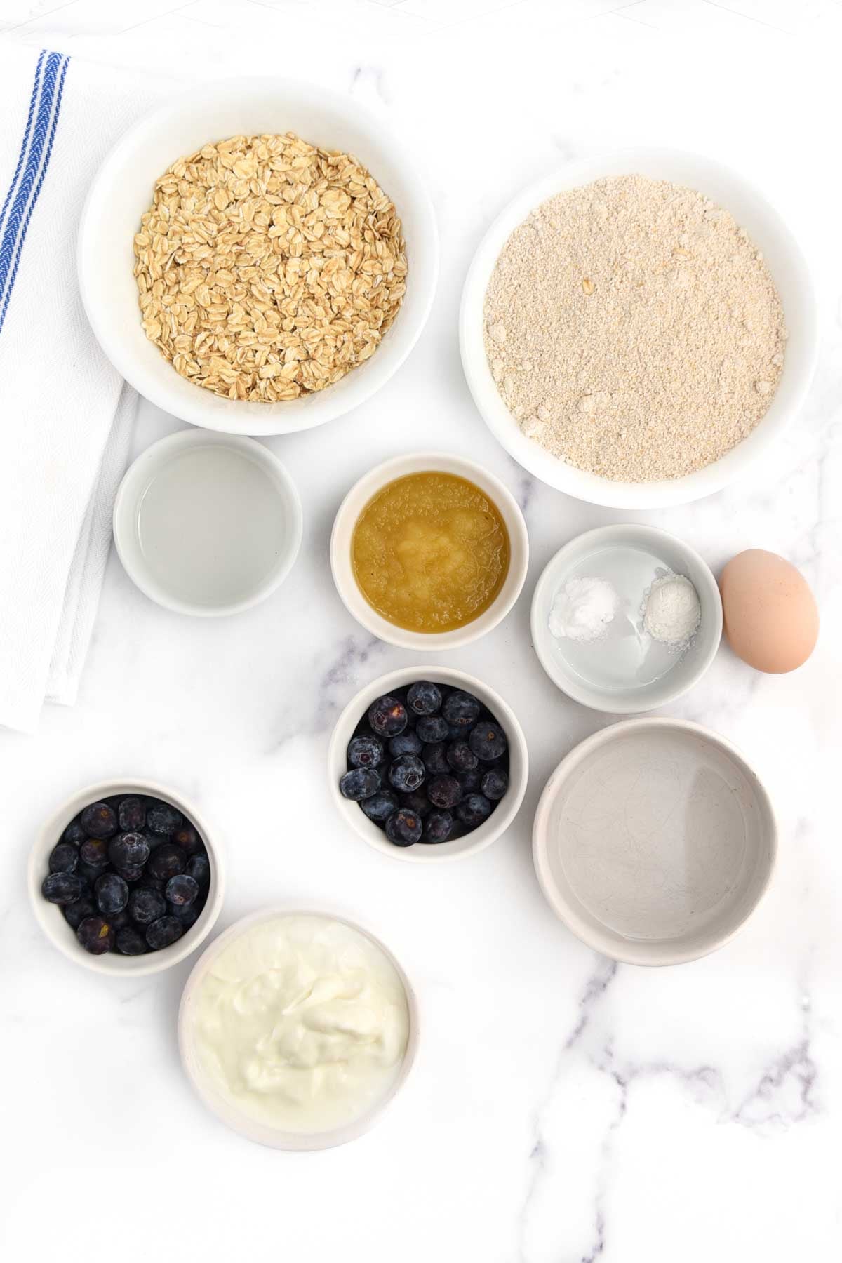 Oat flour, oats, baking soda, baking powder, applesauce, water, coconut oil, egg, yogurt, and blueberries.