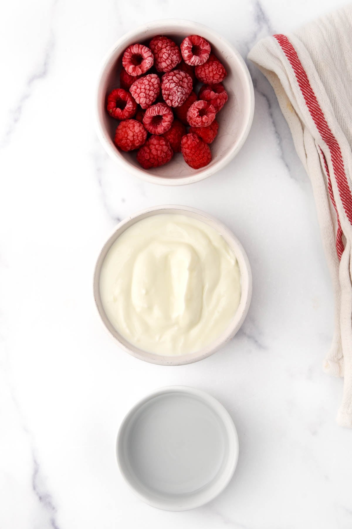 Raspberries, Greek yogurt, and water in bowls.