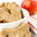Homemade apple bacon dog treats in a bowl and one in front of it.