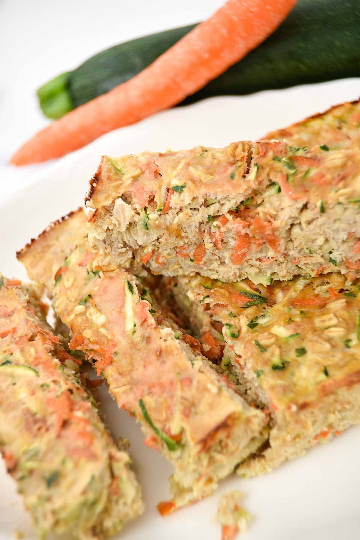 Homemade chicken meatloaf for dogs made with vegetables, oats, and eggs on a platter.