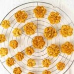 Homemade 3 ingredient dog treats in paw shapes on a wire rack.
