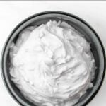 Fluffy homemade whipped cream for dogs in a bowl on a marble surface.