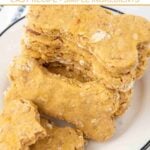 Homemade duck dog treats in bone shapes stacked on a plate.