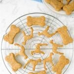Bone and dog-shaped homemade peanut butter banana dog treats on a round wire rack.