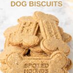 A pile of bone-shaped homemade peanut butter dog biscuits on a marble surface.
