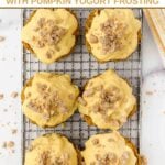 Six pumpkin cupcakes on a wire rack.