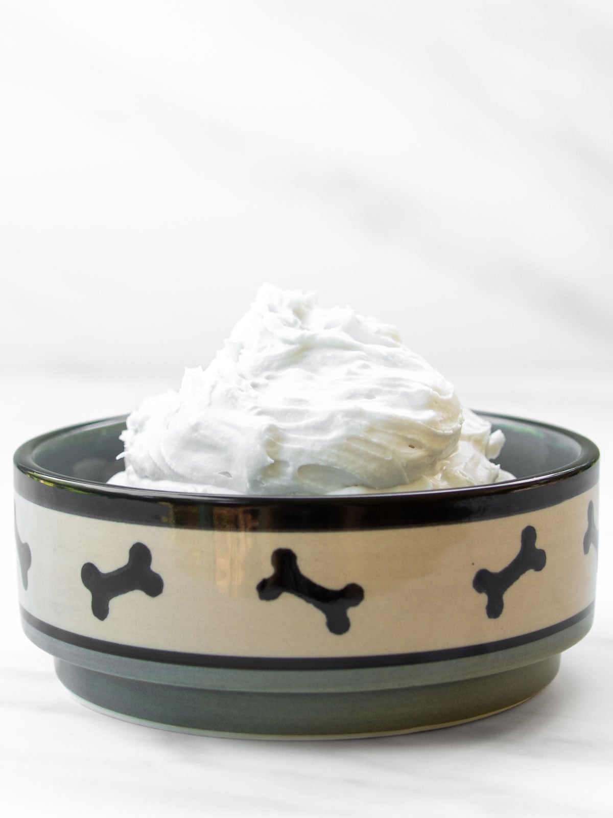 Whipped coconut cream for dogs in a small dog bowl.