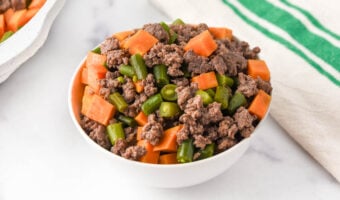 A bowl of homemade dog food made with ground lamb, sweet potatoes, and green beans.