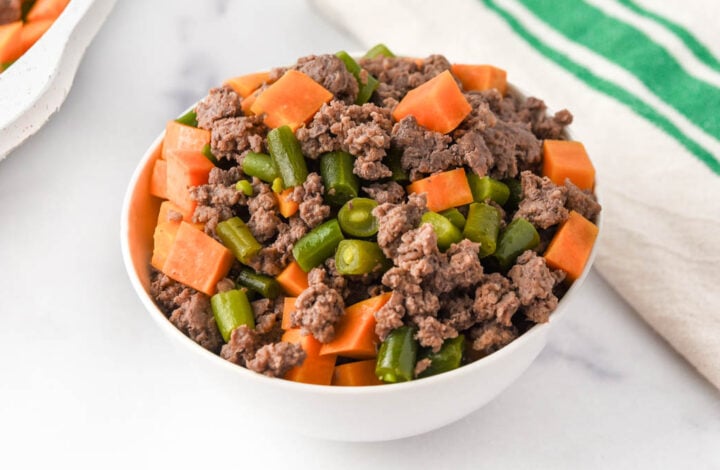 A bowl of homemade dog food made with ground lamb, sweet potatoes, and green beans.