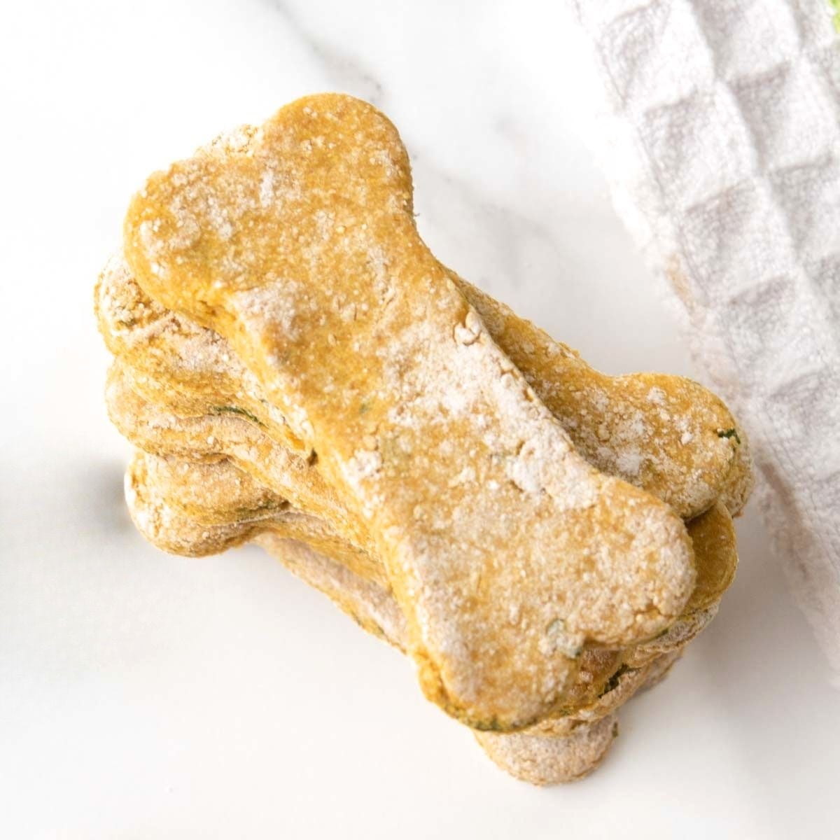 A stack of homemade mint and parsley dog treats on a marble surface.