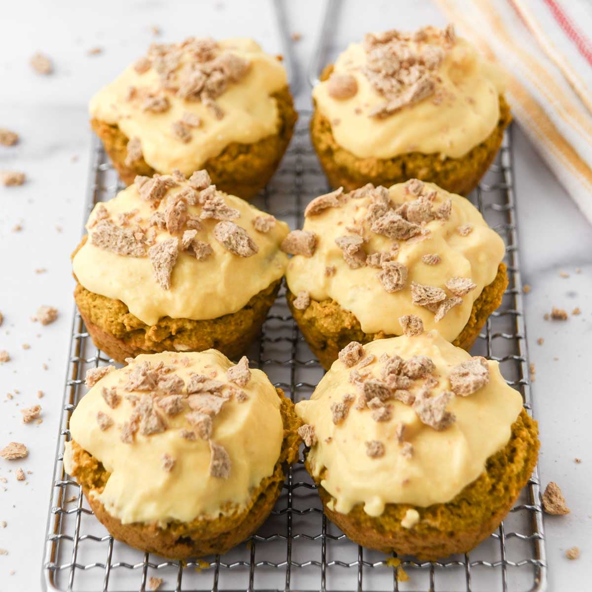 Homemade pumpkin pupcakes with pumpkin yogurt frosting topped with crushed dog treats.