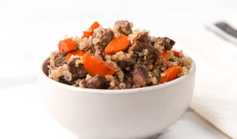Air-fried beef cubes and chopped carrots mixed with quinoa in a bowl.