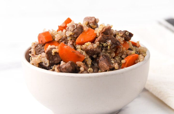 Air-fried beef cubes and chopped carrots mixed with quinoa in a bowl.