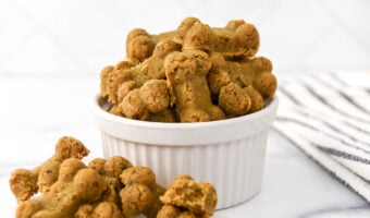 Homemade anchovy dog treats shaped like bones in a small bowl and next to it.