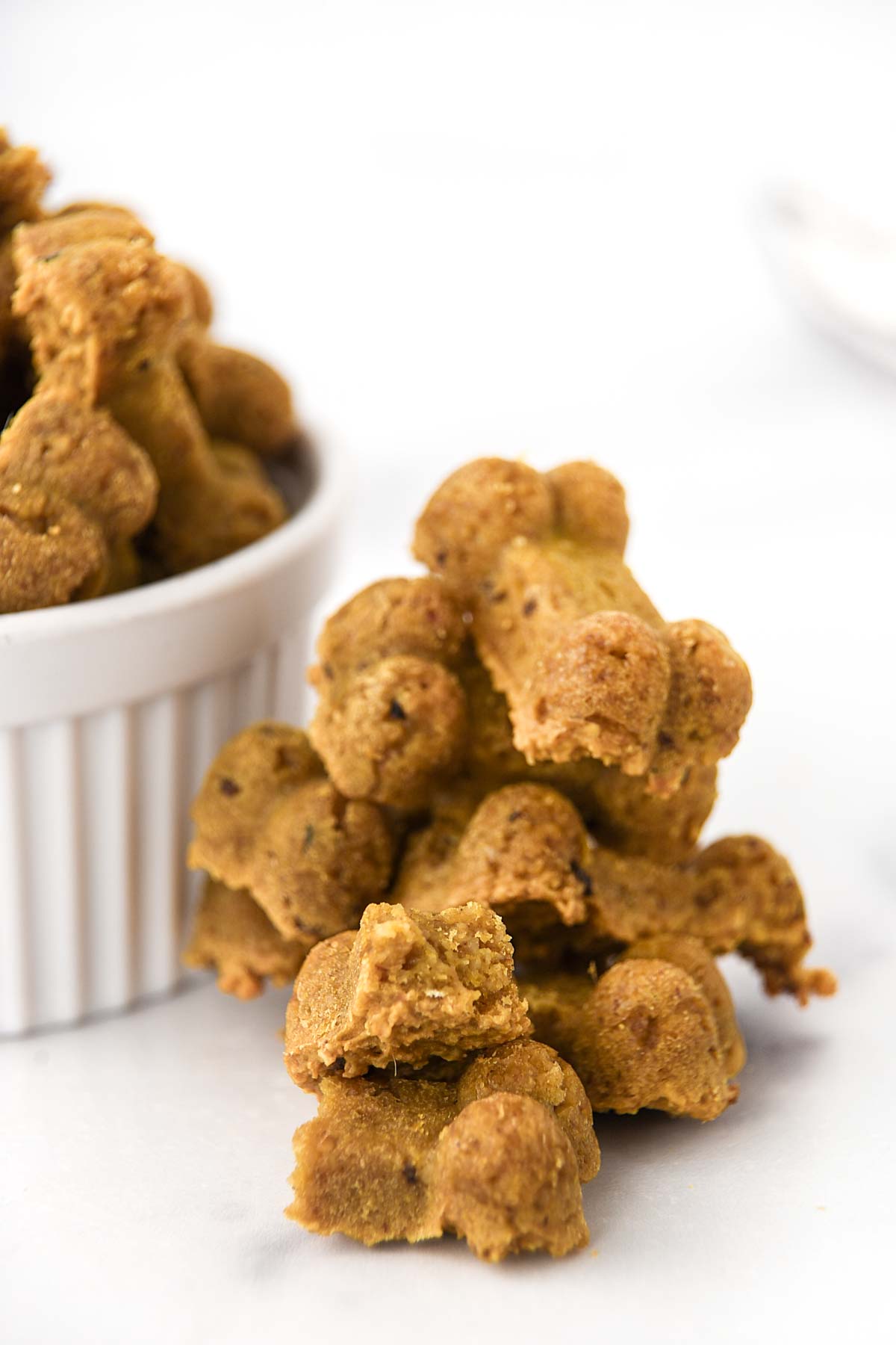 Homemade anchovy dog treats in a stack next to a bowl of them.